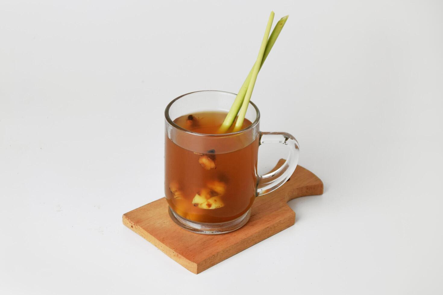 Hot red ginger drink in glass on wooden coaster and isolated white background photo