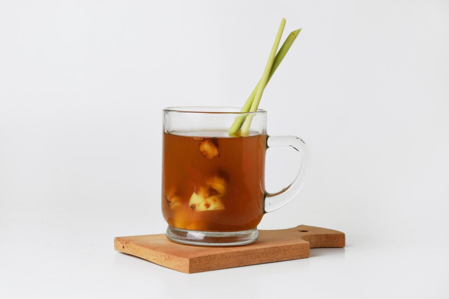 Hot red ginger drink in glass on wooden coaster and isolated white background photo