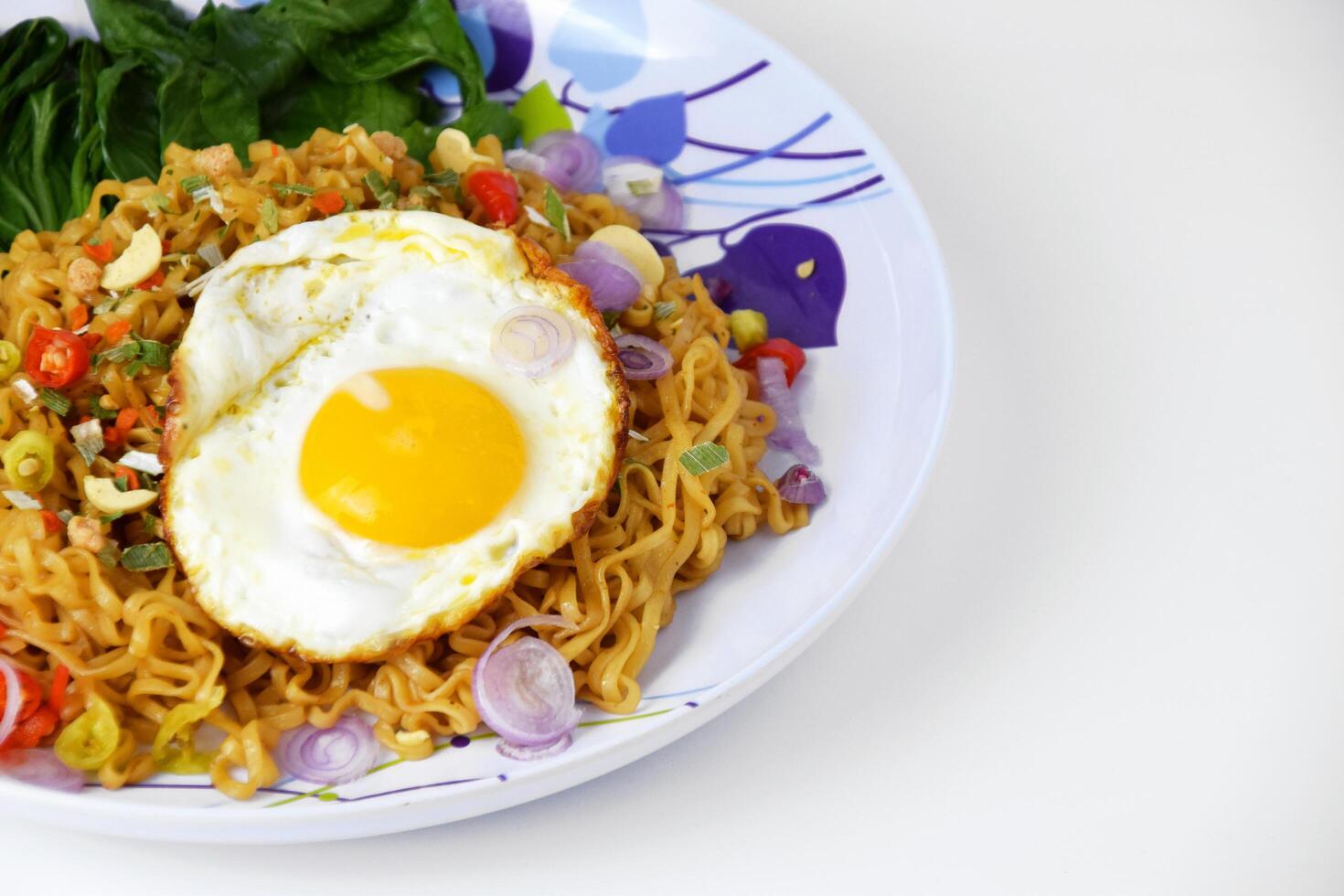 Fried noodles with sunny side up egg and mixed vegetables on a plate photo