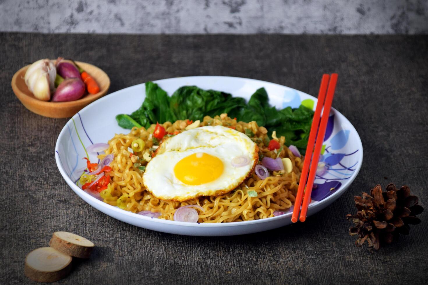 Fried noodles with sunny side up egg and mixed vegetables on a plate photo