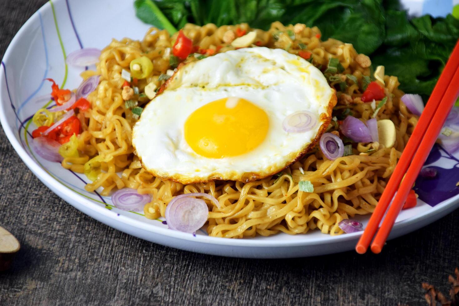 Closeup photo of fried noodles with sunny side up egg and mixed vegetables