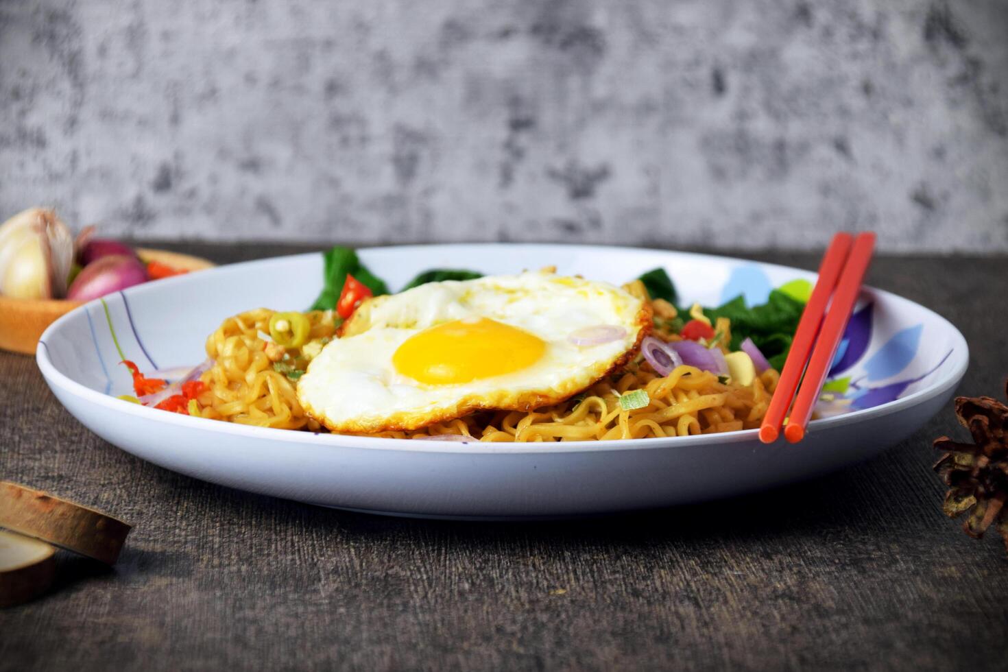 Fried noodles with sunny side up egg and mixed vegetables on a plate photo