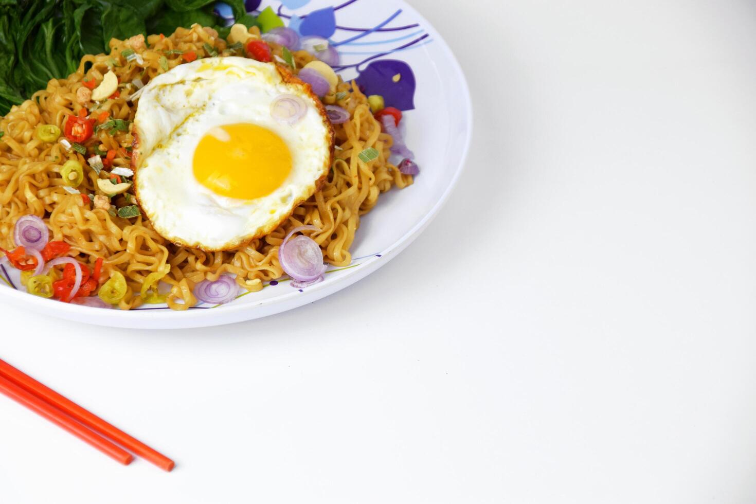 Fried noodles with sunny side up egg and mixed vegetables on a plate photo