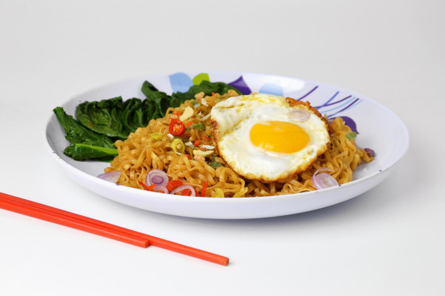 Fried noodles with sunny side up egg and mixed vegetables on a plate photo