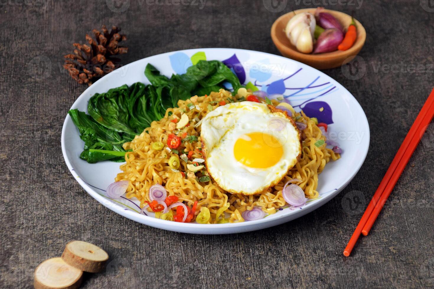 Fried noodles with sunny side up egg and mixed vegetables on a plate photo