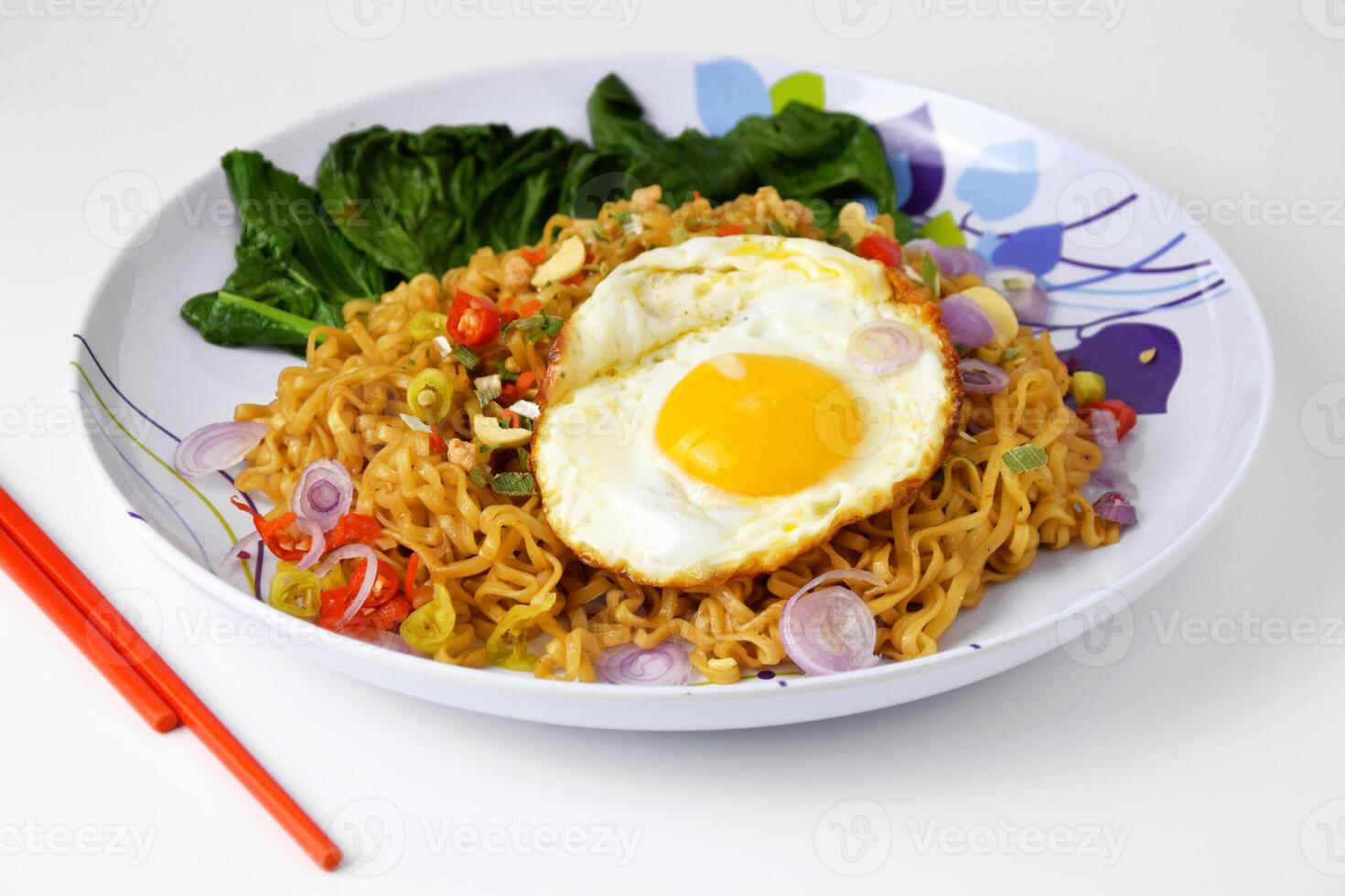 Fried noodles with sunny side up egg and mixed vegetables on a plate photo