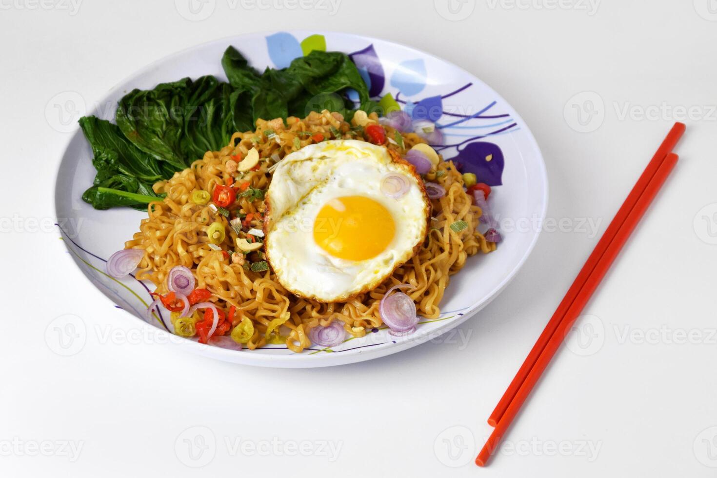 Fried noodles with sunny side up egg and mixed vegetables on a plate photo