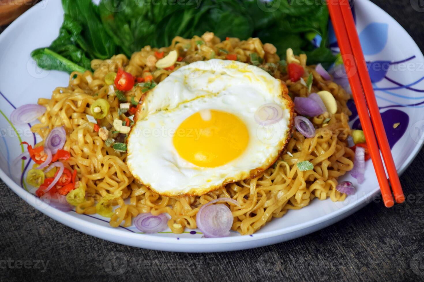 Closeup photo of fried noodles with sunny side up egg and mixed vegetables