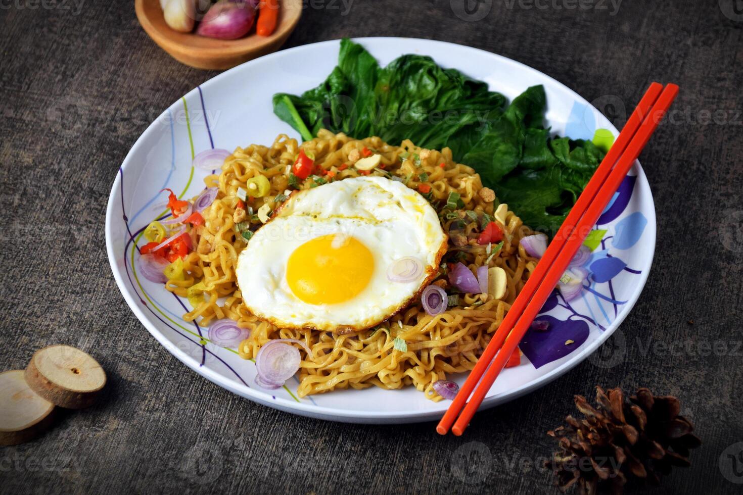 Fried noodles with sunny side up egg and mixed vegetables on a plate photo