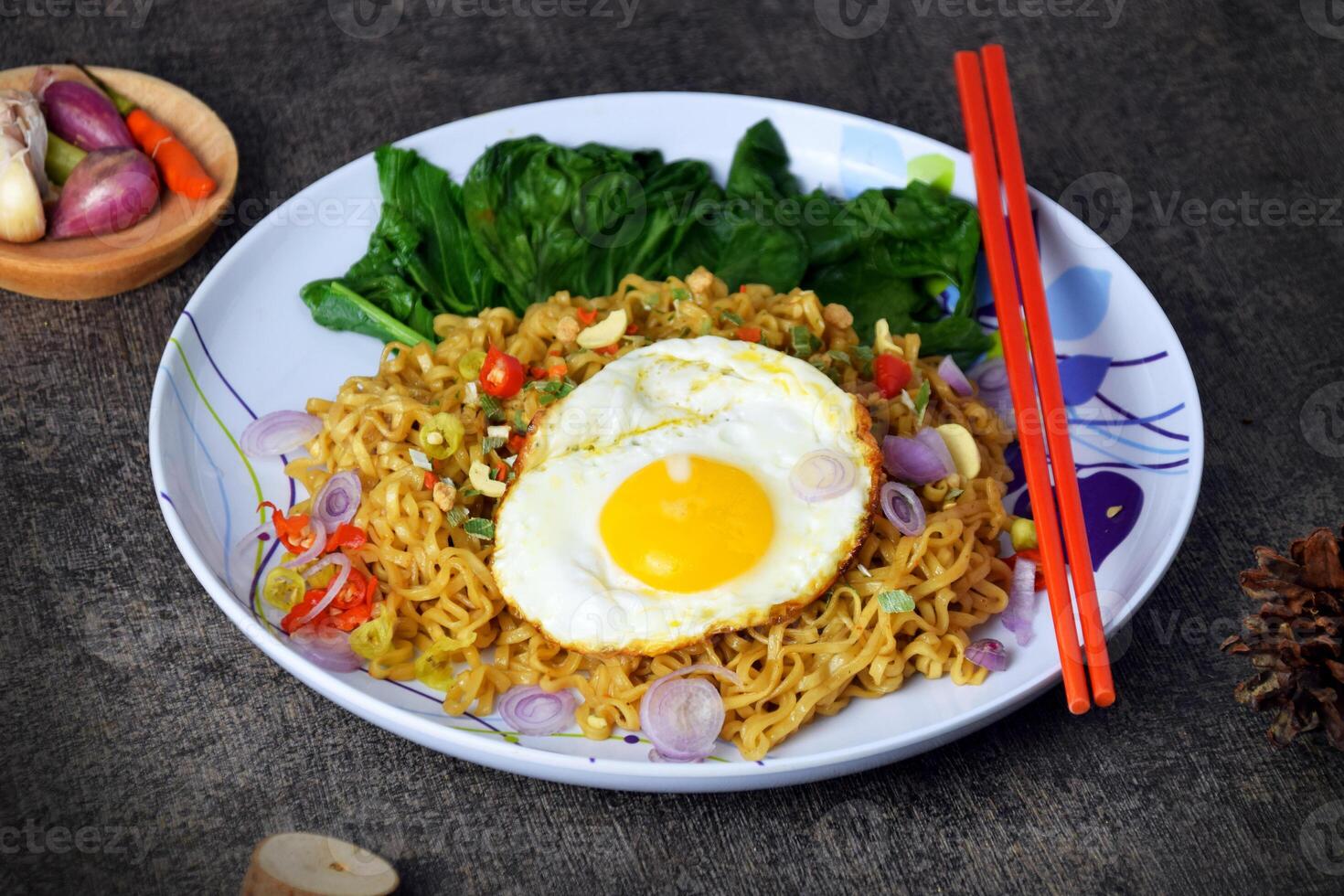 Fried noodles with sunny side up egg and mixed vegetables on a plate photo