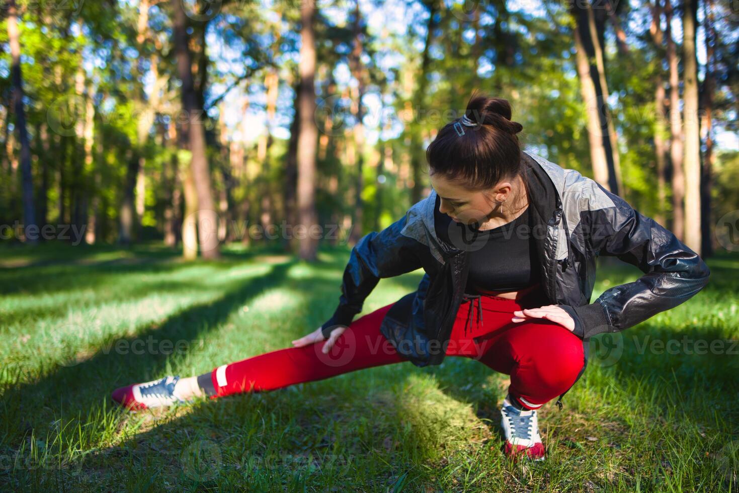 Young woman in tracksuit doing stretching in the woods in early spring. photo