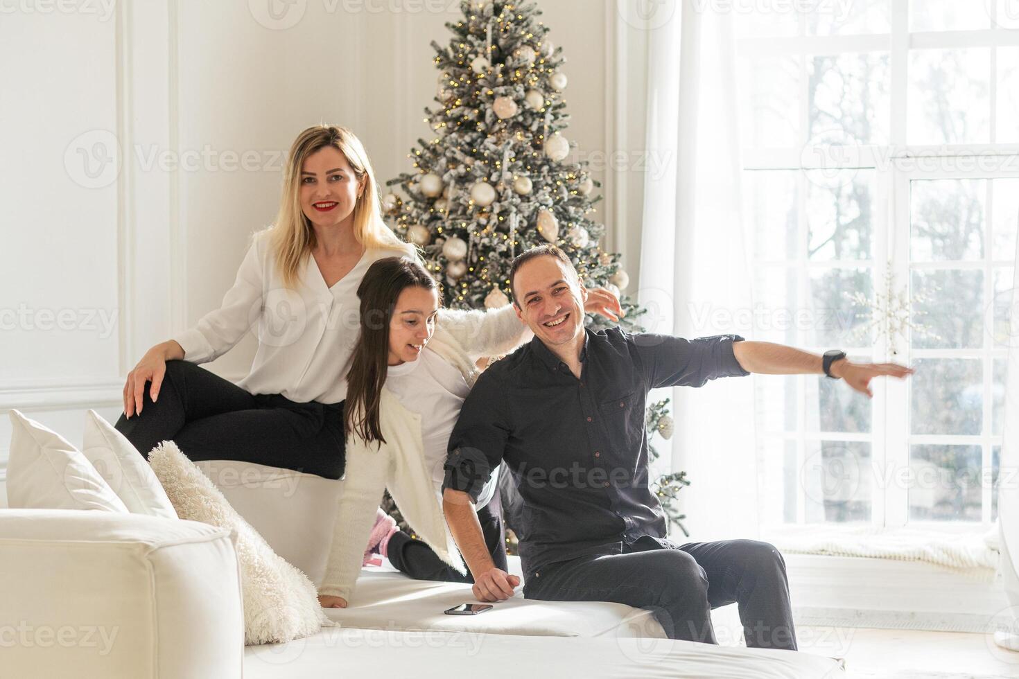 family, winter holidays and people concept - happy mother, father and little daughter decorating christmas tree at home photo