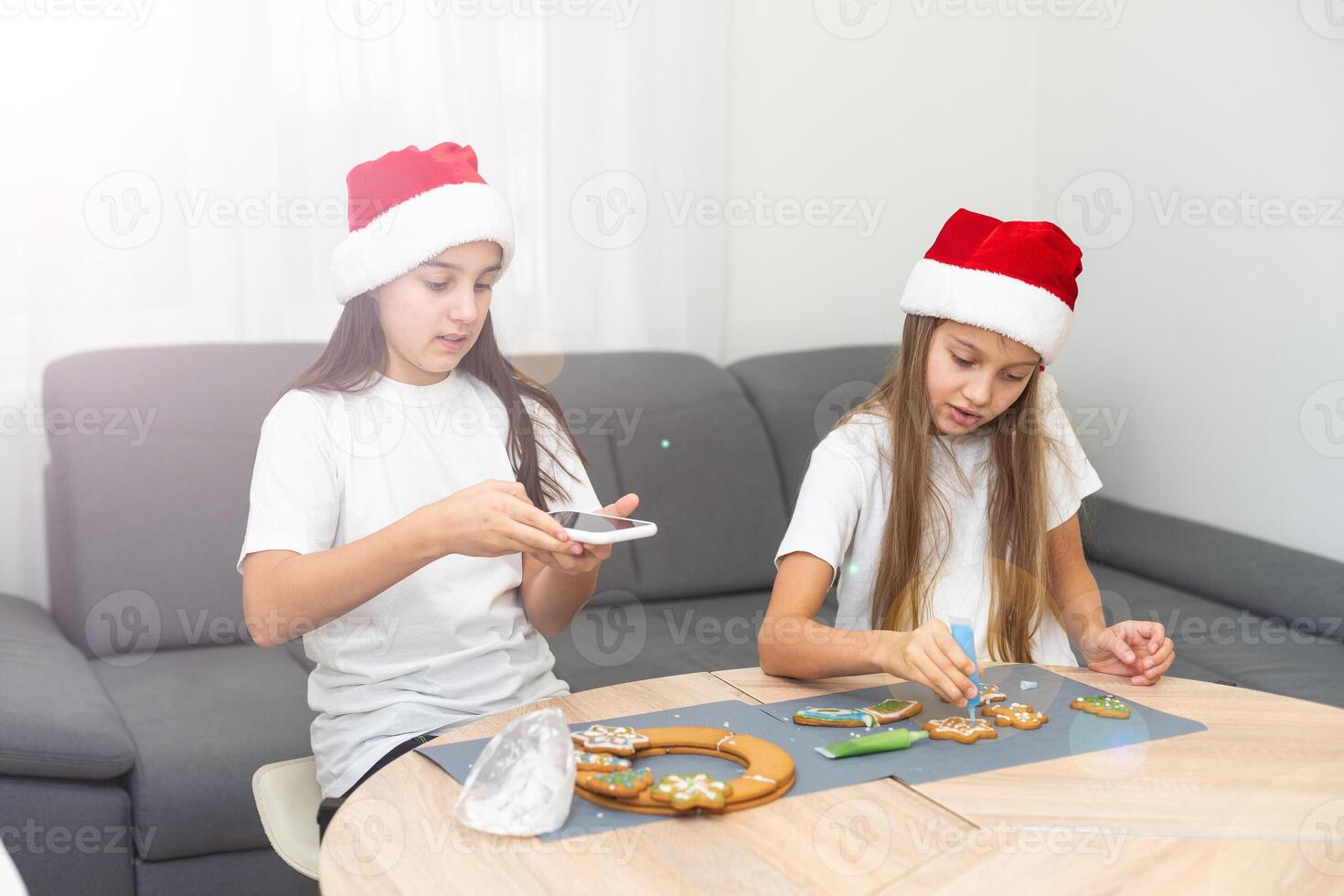 Two girls sisters are playing around in the kitchen after making Christmas cookies, they draw with flour on the table and on their faces. Christmas, New Year concept photo