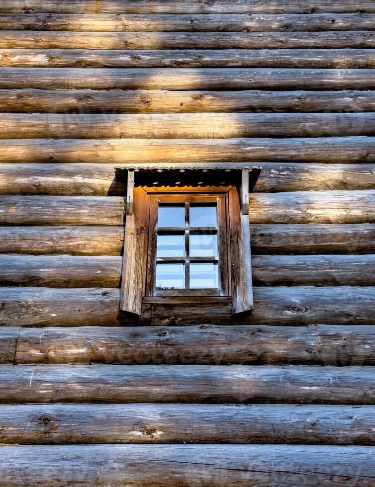 A close-up of beautifully carved wooden windows on a traditional Russian log house , izba. The ornate shutters, detailed woodwork, and charming flower bed create a picturesque, rustic ambiance photo