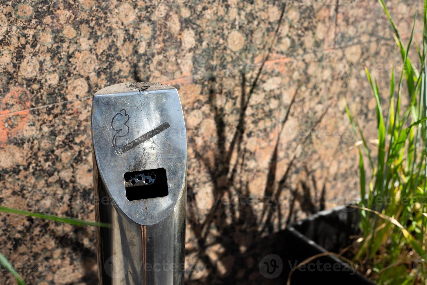 Street metal pole ashtray in smoking area near the building, social problem of cigarette smoking addiction, hole for extinguishing cigarettes on street in response to bad habit photo