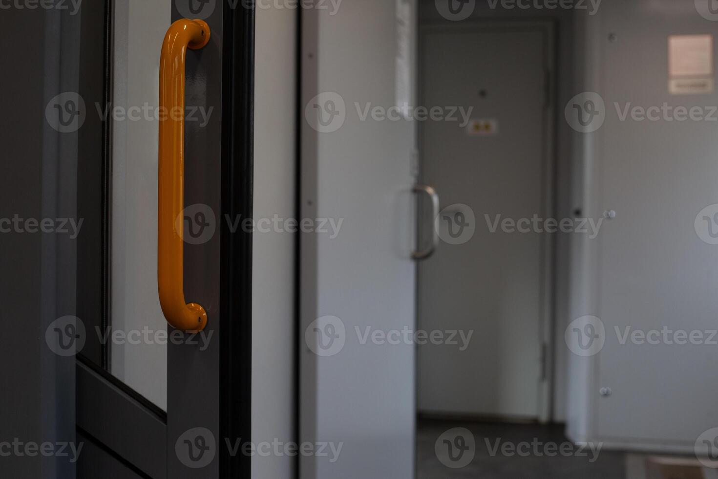 Open door with orange handle on train, door that opens passage for passengers on electric train, door folding into the wall on train to access corridor photo