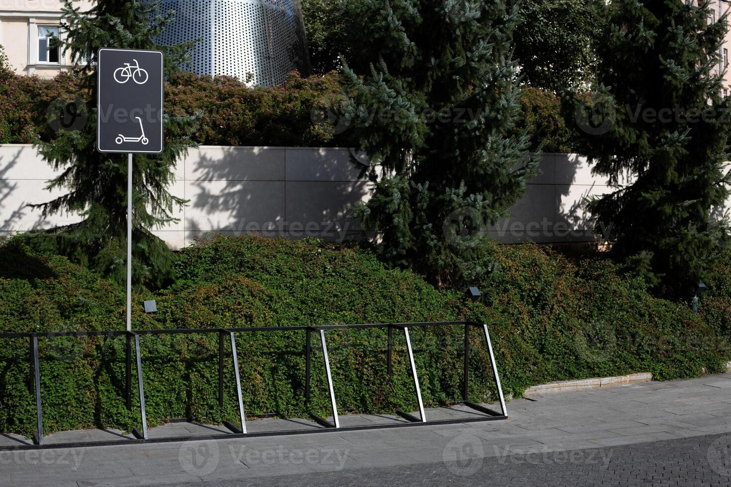 Parking area for bicycles and scooters with mounts for the safety of personal vehicles. Sign on pole shows where to park scooters and bicycles in public park photo