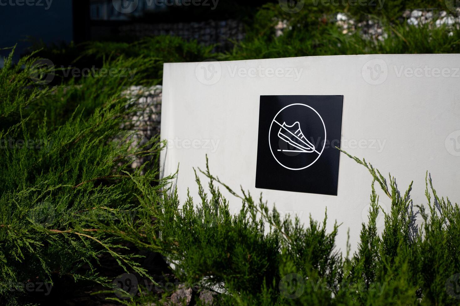Sticker with crossed out sneaker on wall of decorative structure in public park, prohibition of stepping on surface in park, cleanliness and care photo