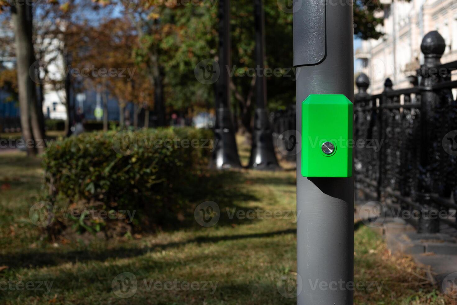 Control panel with button for pedestrians on pole, activate green traffic light signal for crossing the road along street in modern city against the backdrop of park photo