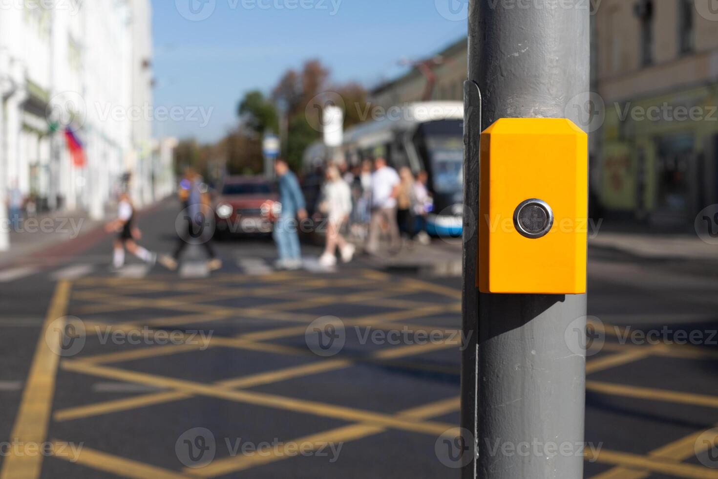 Button for changing traffic light signal for pedestrians to cross an intersection. Control panel for waiting to cross the road hangs on pole on the background of people cross road photo