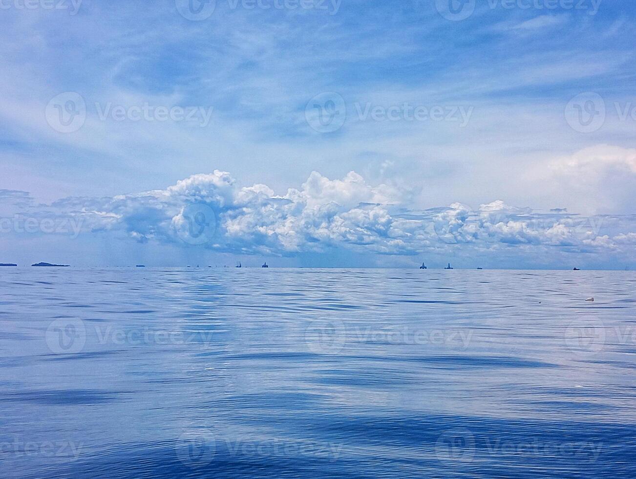 A blue sky with clouds and a boat in the water photo
