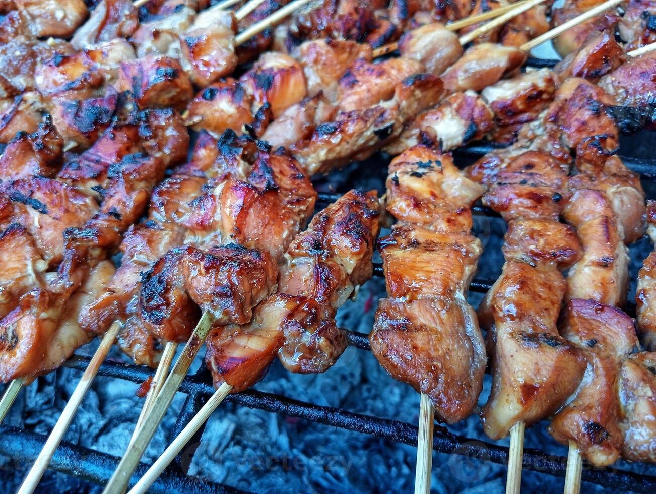A grill with skewers of chicken on it photo