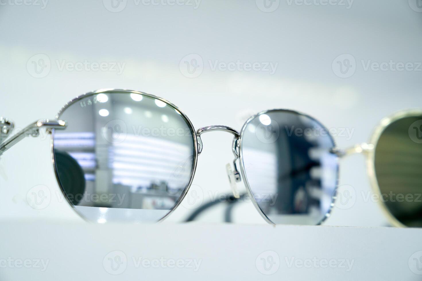 Close-up of round sunglasses with reflective silver lenses, highlighting stylish sleek modern design and metallic frames, fashion-forward accessories, minimalist display, retail ambiance photo