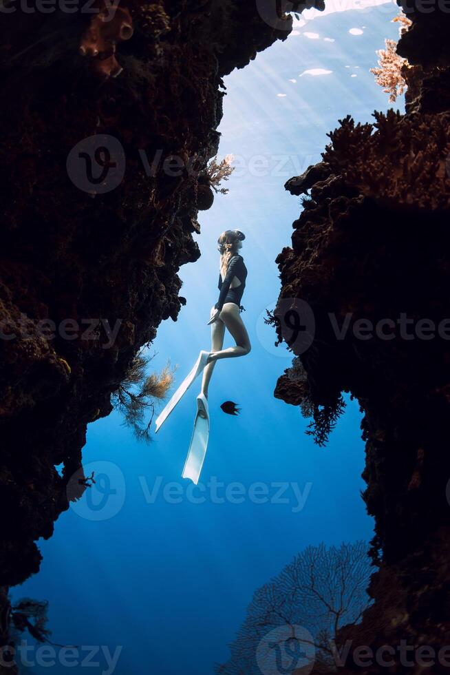 Woman freediver glides in underwater cave on Menjangan island, Bali. photo