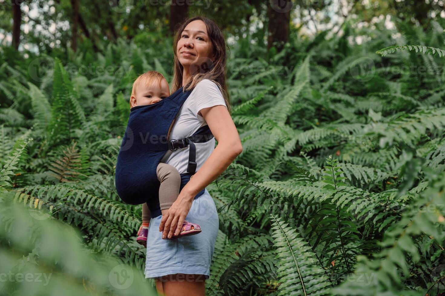 Mother with her cute baby daughter in park between fern leaves photo