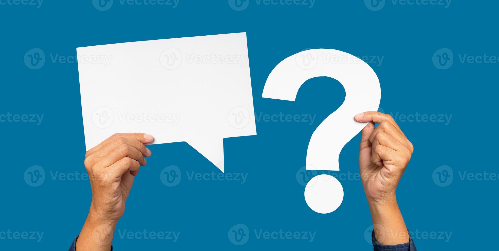 Hand holding a blank white speech bubble and a white question mark on a blue background photo