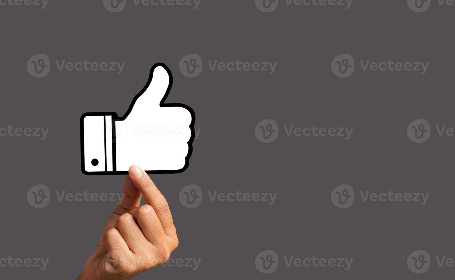 Customer service rating, satisfaction concept. Hand holding a thumbs up a symbol against a gray background photo
