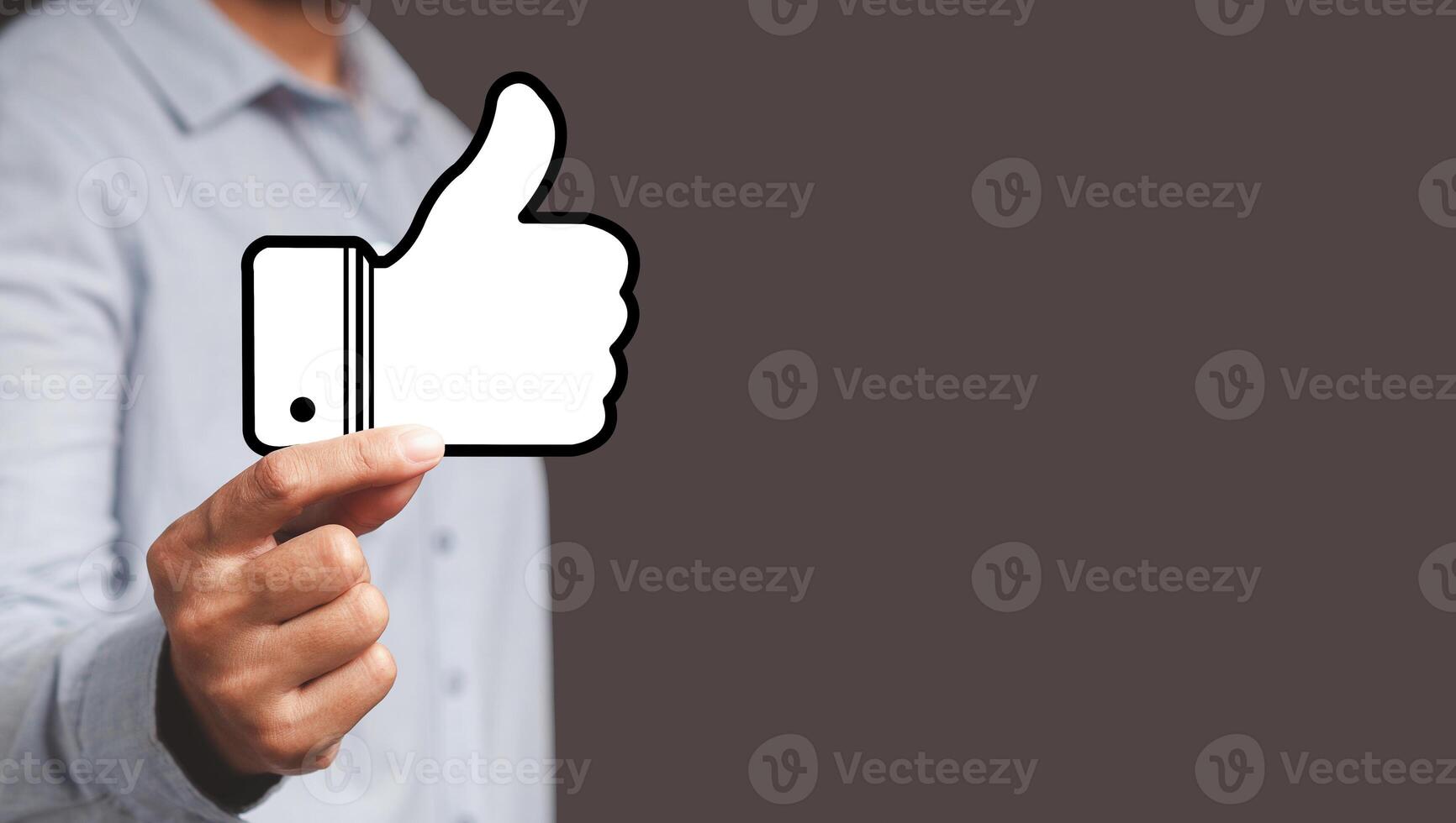 Hand holding a paper thumbs up against a gray background photo
