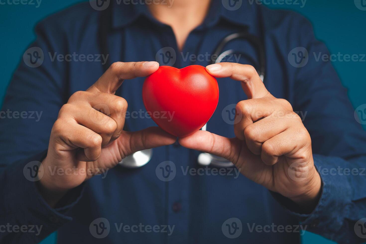 Hand of a doctor holding a red heart shape while standing in the hospital or clinic. photo