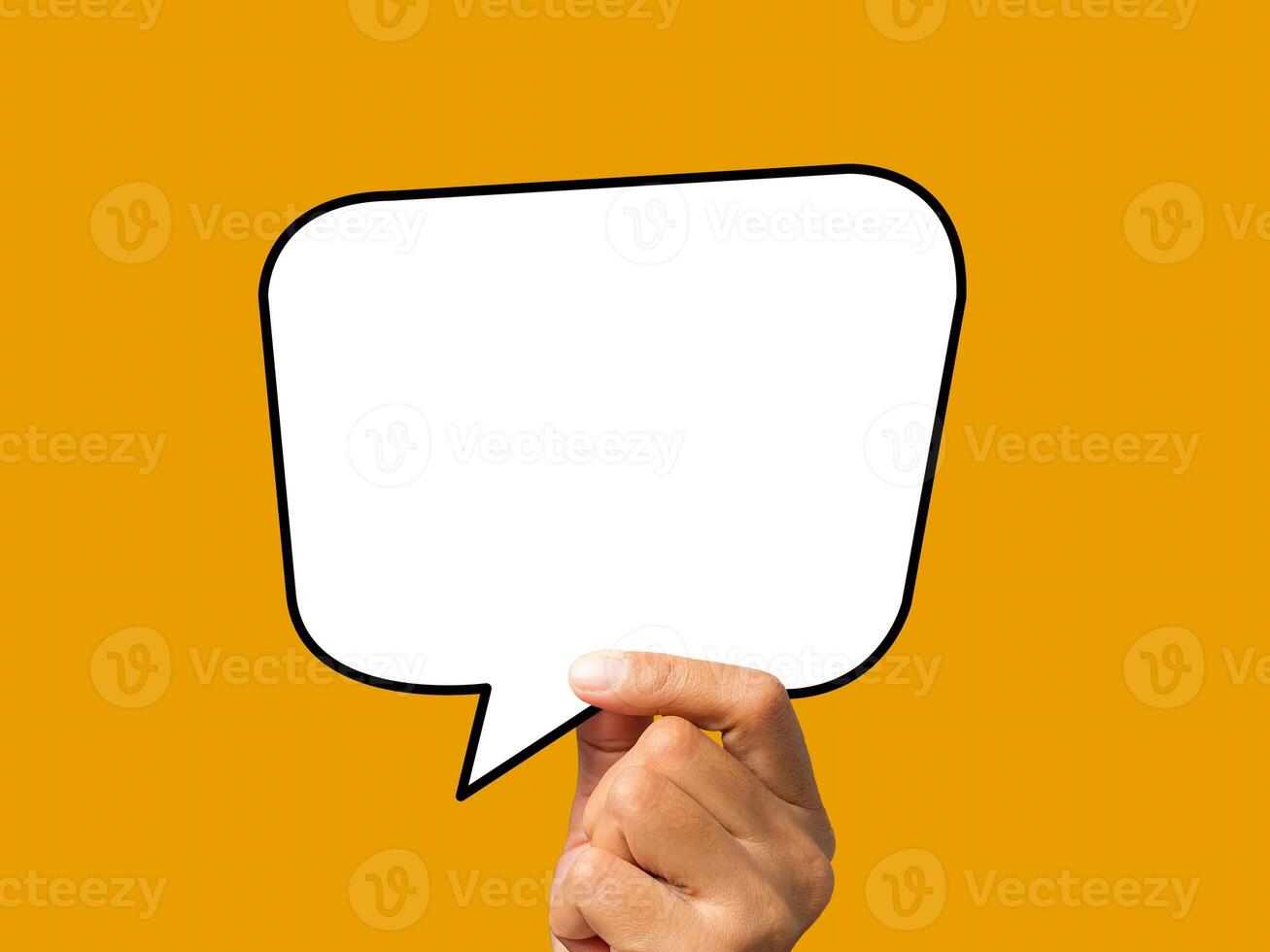 Hand holding of an empty white speech bubble against an orange background. photo