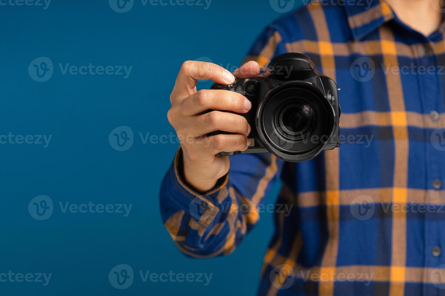 Close-up of hand holding the digital camera while standing on a blue background photo