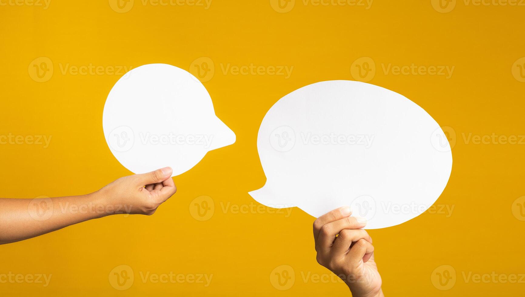 Hand holding of an empty white speech bubble against a yellow background. photo