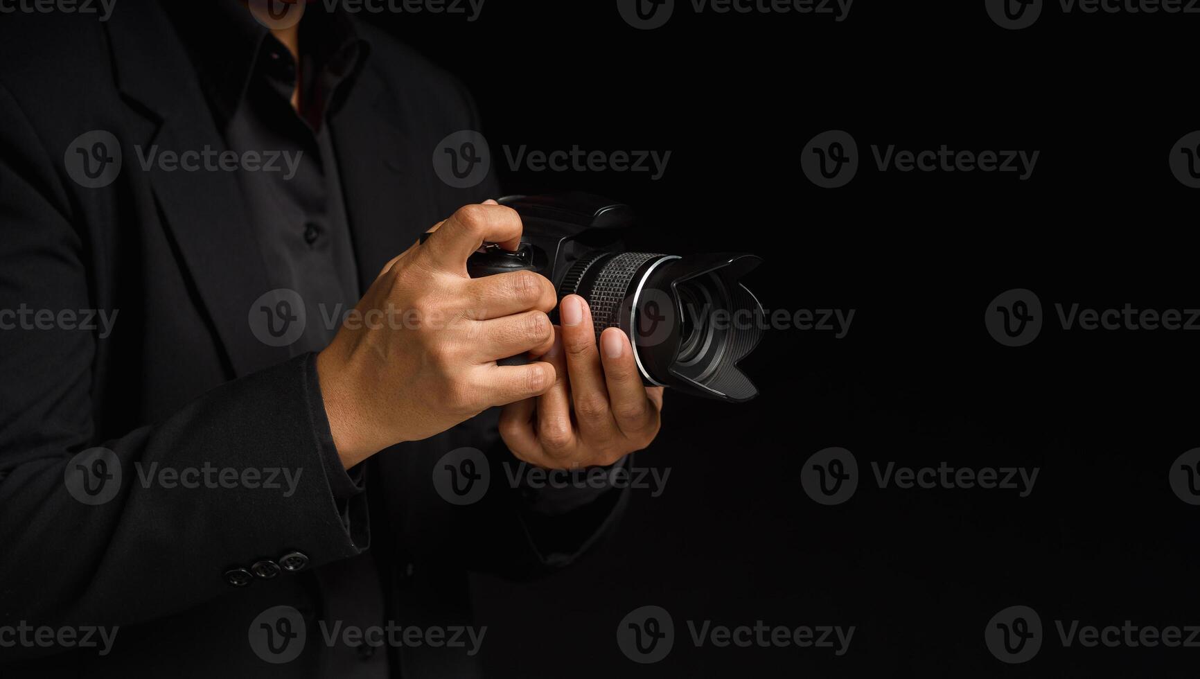 Close-up of hand holding the digital camera while standing on a black background photo