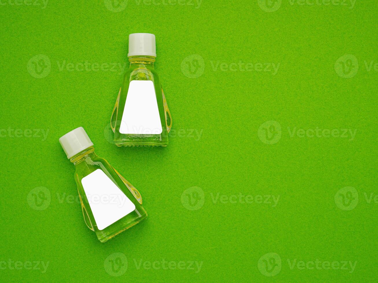 Small bottle containers with blank labels for branding mockup isolated on a green background. photo