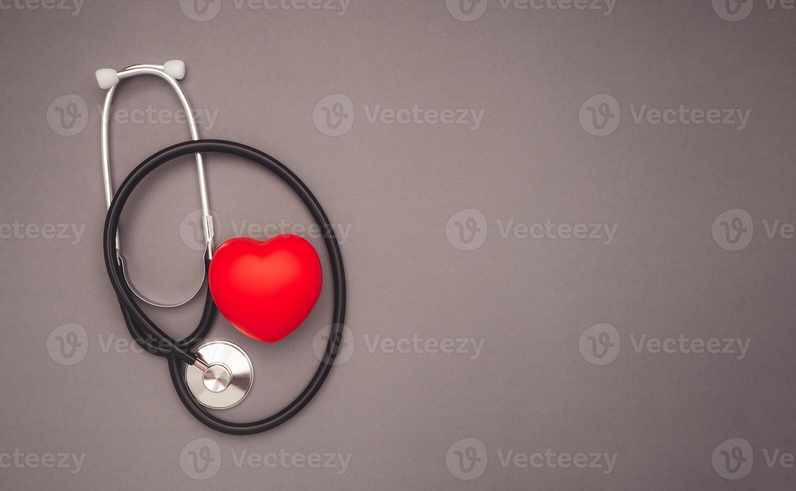 A red heart shape with a stethoscope over a gray background photo