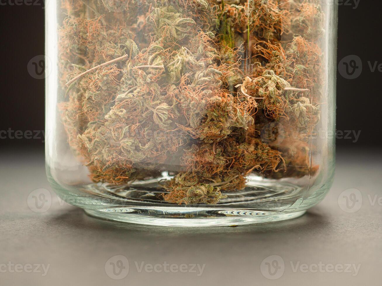 Dry cannabis buds flower in a jar glass with a black background. photo