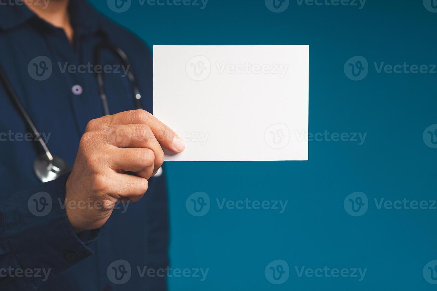 Doctor hand holding a blank white paper while standing on a blue background photo
