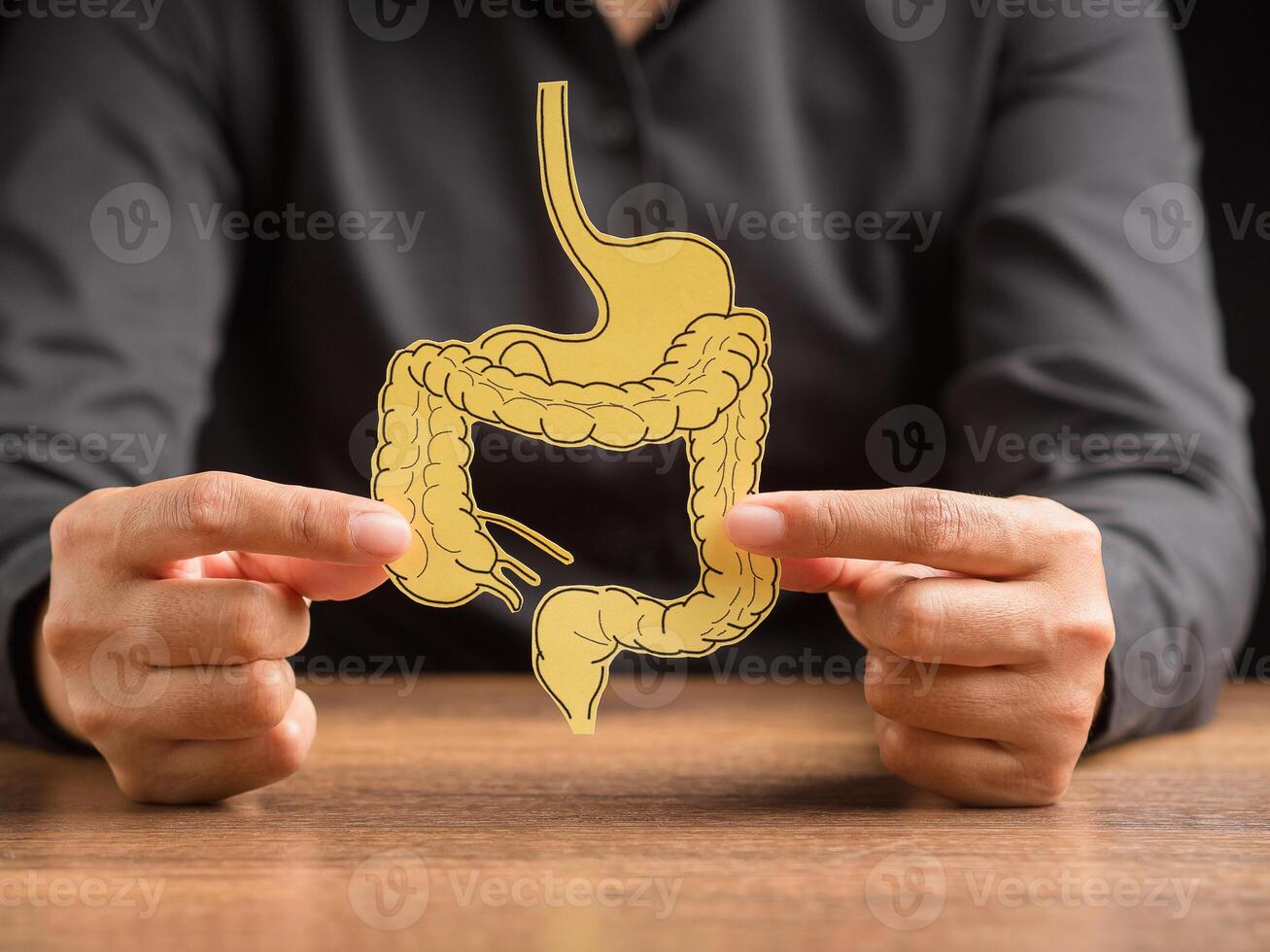 Hand holding a large intestine shape made from yellow paper photo