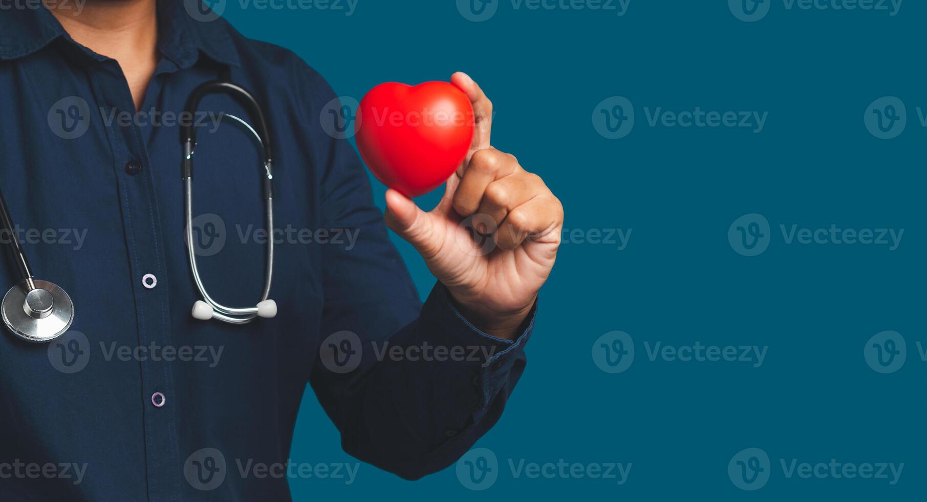 Hand of a doctor holding a red heart shape while standing on a blue background. photo
