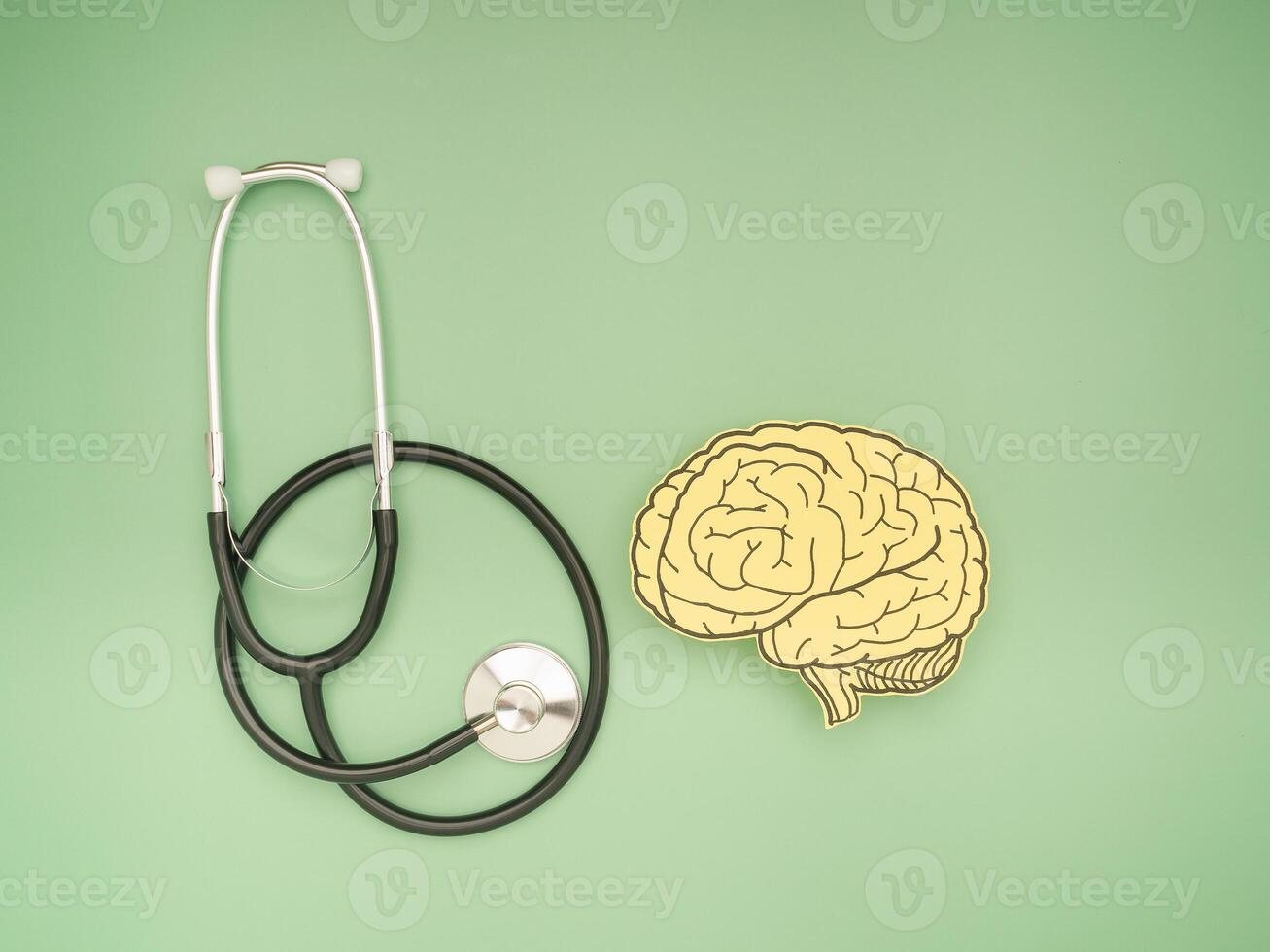 A stethoscope and brain shape made from paper over a green background photo