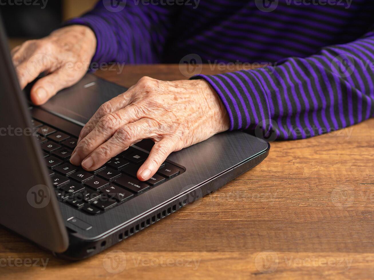 Focus on the hand of a senior woman using a laptop for searching data on the internet photo