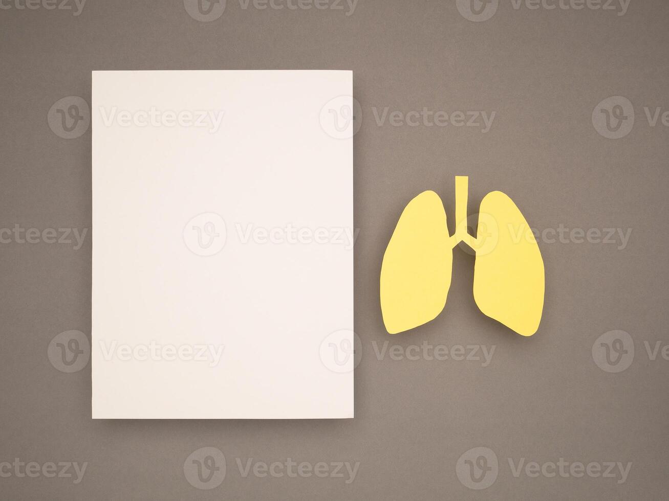 Lungs shape made from yellow paper and a blank white paper on a gray background photo
