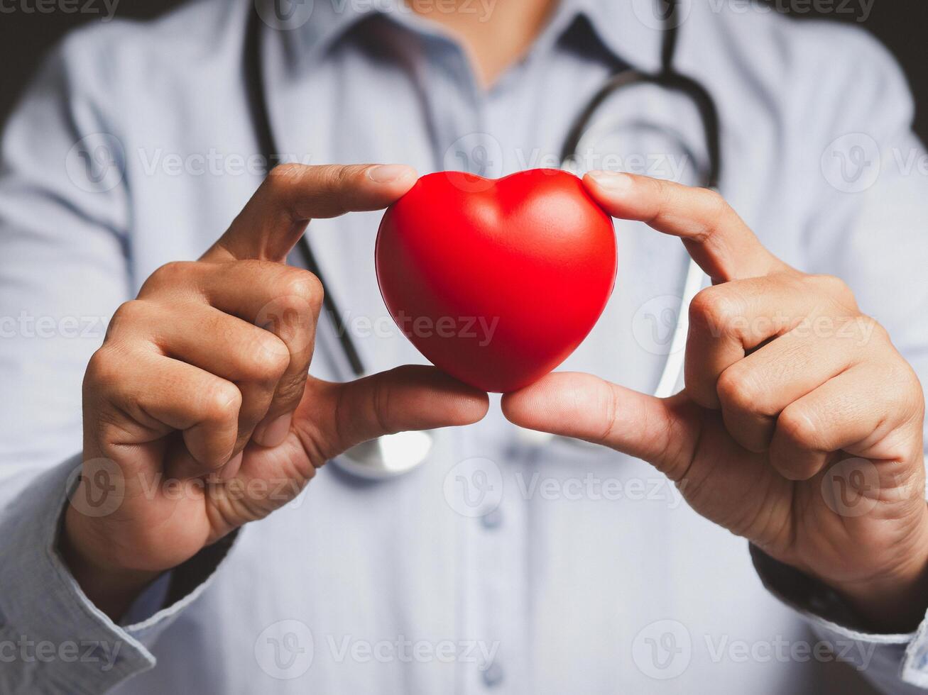 Hand of a doctor holding a red heart shape while standing in the hospital or clinic. photo
