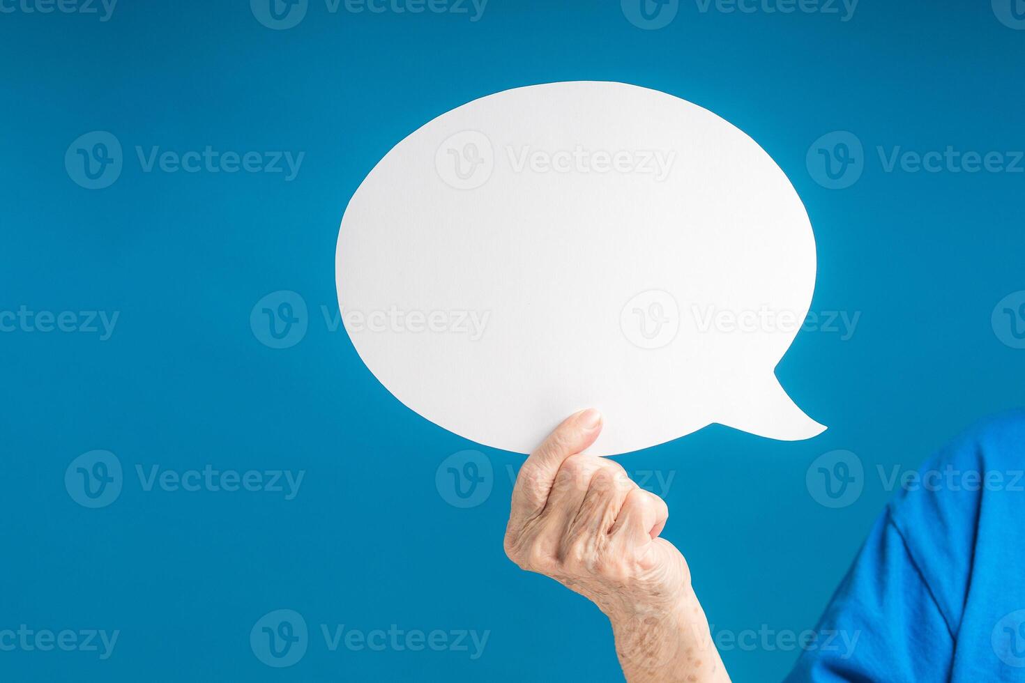 Hand holding of a blank white speech bubble on a blue background photo