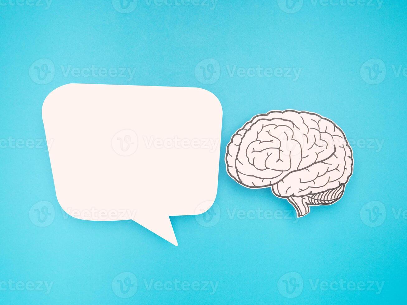 White speech bubble and a brain shape made from paper on a blue background photo