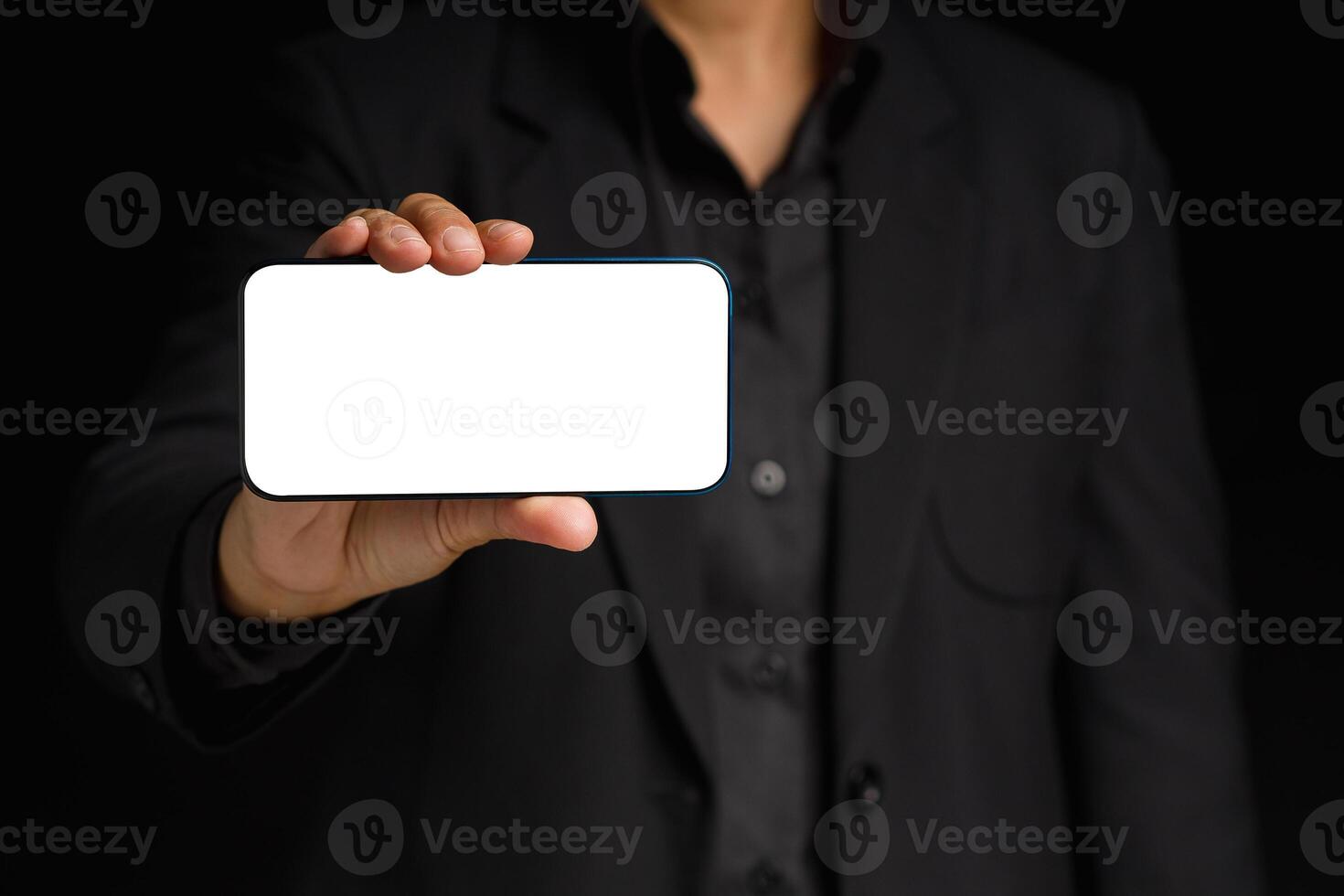 Hand holding a blank screen smartphone while standing on a black background photo